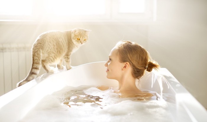 お風呂に入る女性と猫