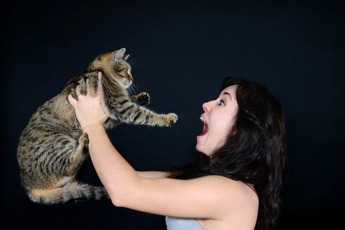 叫ぶ女性に抱かれる猫