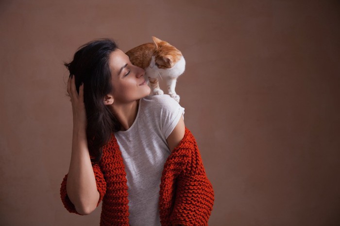 女性の肩に乗りキスをする猫