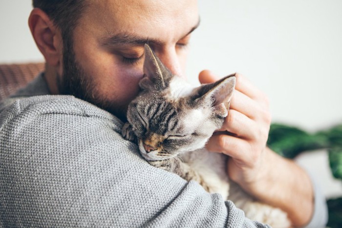 目を閉じて猫を抱きしめる男性