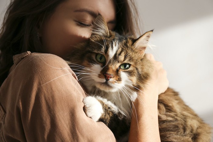 目を閉じて猫を抱っこしている女性
