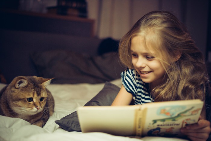 子供が猫に絵本を読み聞かせている