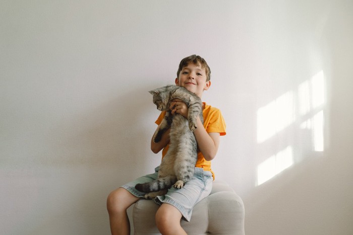 猫を抱き上げる少年