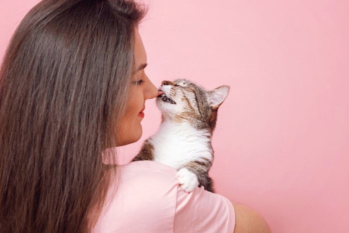 女性の鼻を舐める猫