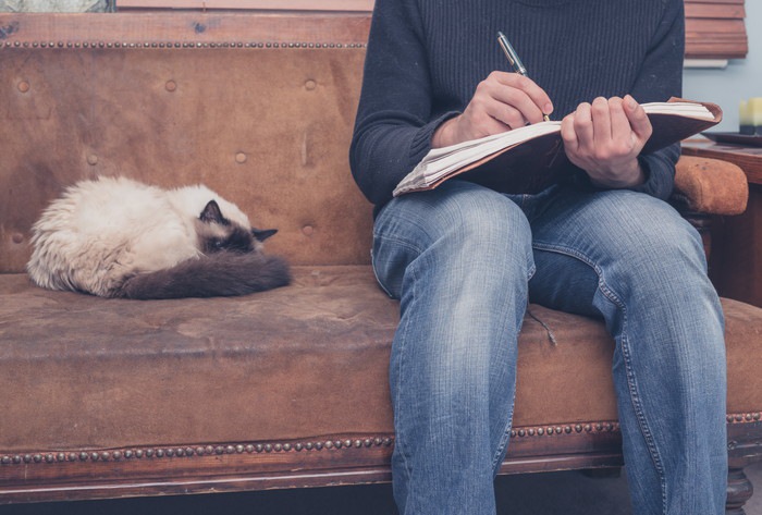 日記を書く男性と猫