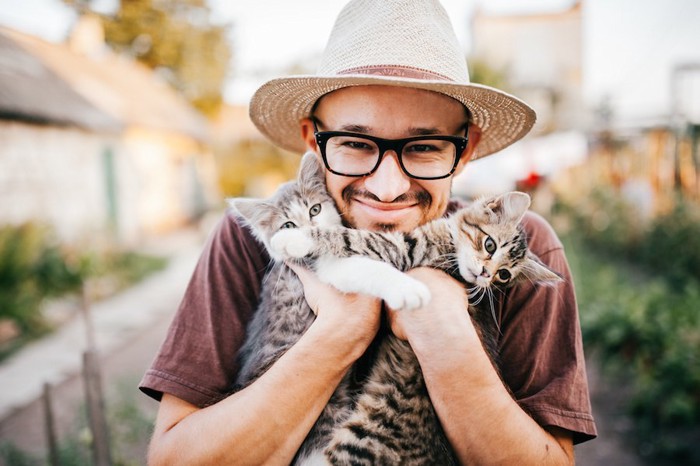 2匹の猫を抱えている笑顔の男性