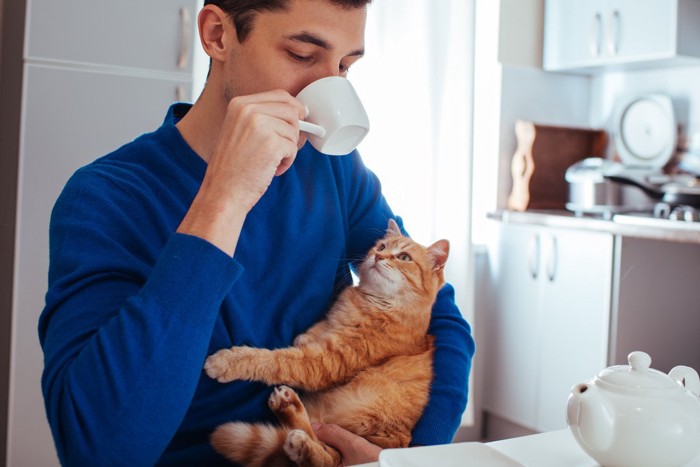 コーヒーを飲む飼い主さんと猫