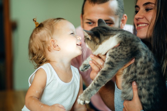 猫を抱っこする女性と家族