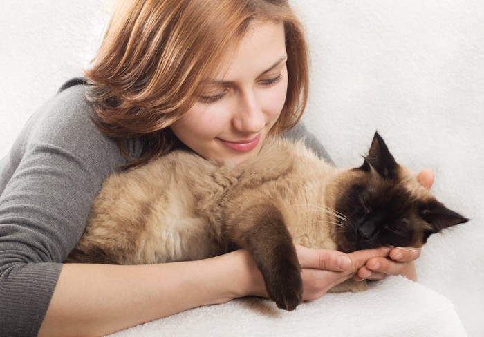 寝ている猫を抱きしめる女性