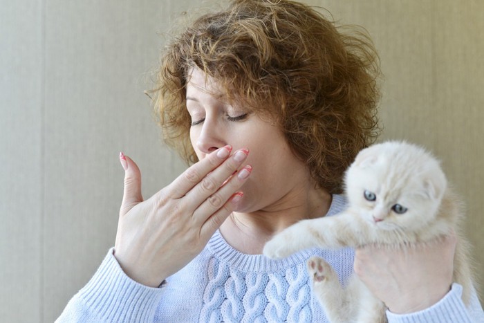 猫を抱っこしながら咳をする女性