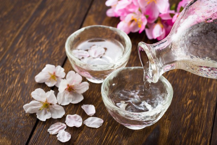 グラスに注がれる日本酒と桜の花びら