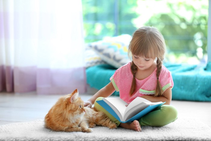 本を読んでる少女と猫