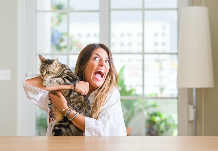 猫を抱きながら大声で騒いでいる女性