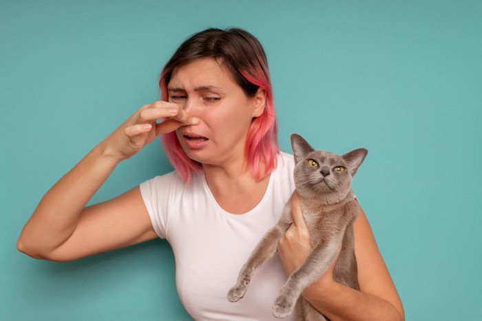 鼻をつまむ女性と猫