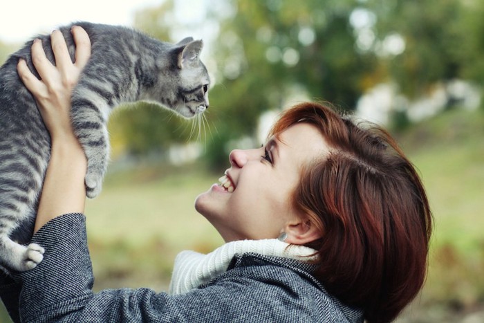 笑顔で猫を抱き上げる女性