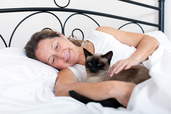ベッドの上にいる女性と猫