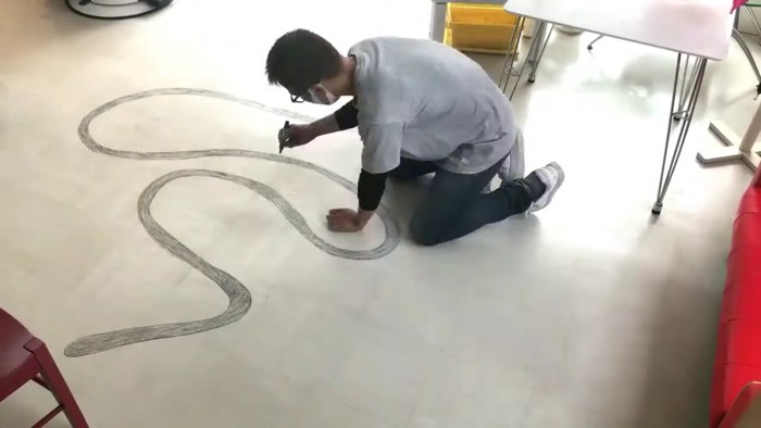 床に蛇の絵を描く人間