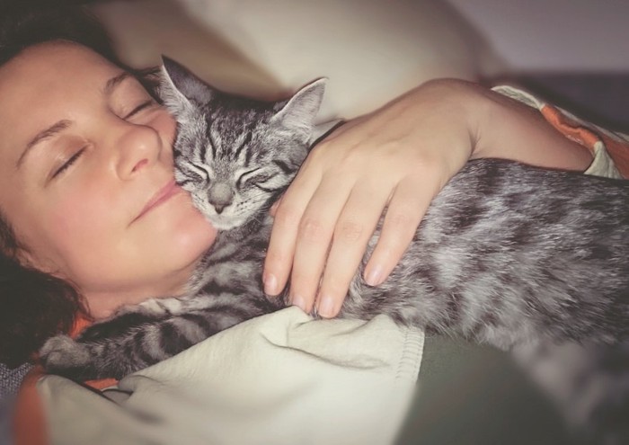 女性の上で一緒に眠る猫