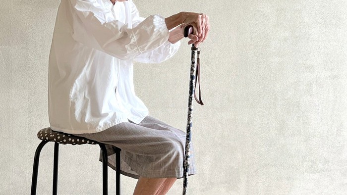 杖を持って椅子に腰かける高齢女性