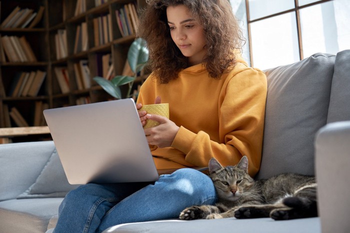 パソコンを見ている女性と猫