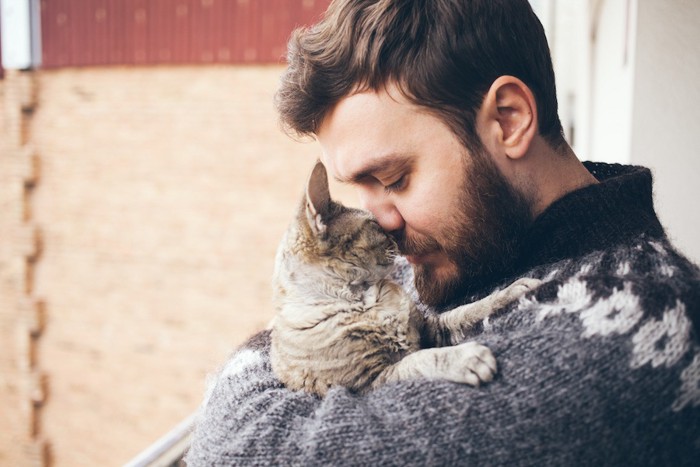 猫を抱きしめてキスをする男性