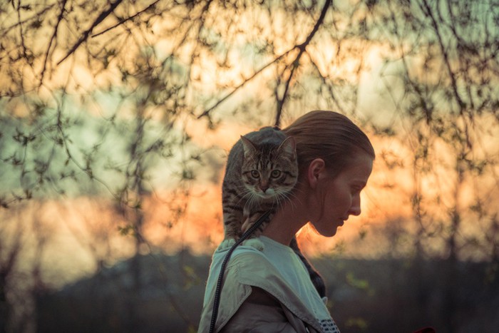 猫を肩に乗せ散歩する女性