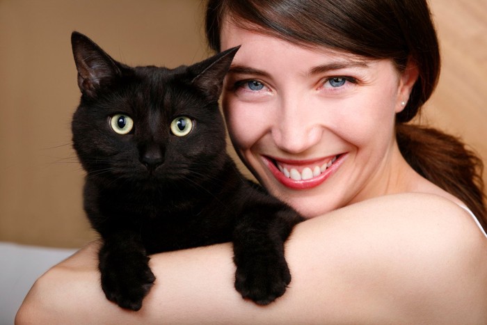 女性に抱かれる可愛い黒猫
