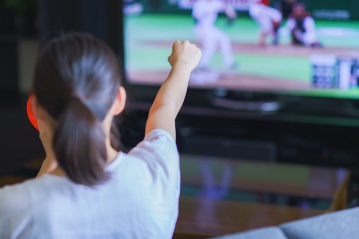 テレビで野球を見て応援している女性