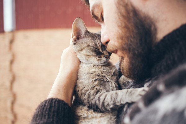 髭の男性に抱っこされる猫