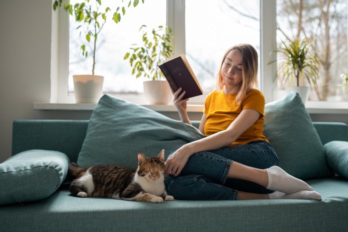ソファでリラックスする女性と猫