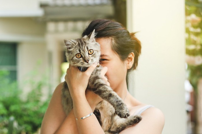 猫を顔の前に抱き上げる女性