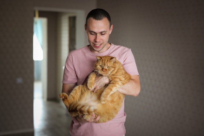 太った猫を抱く男性