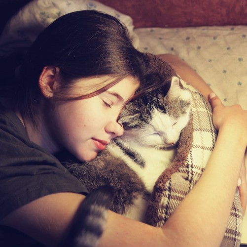 猫を抱きしめて眠る女性