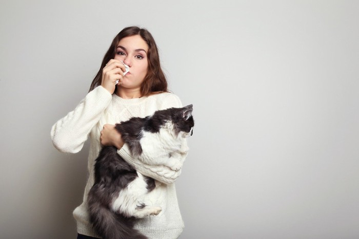 猫を抱く猫アレルギーの女性
