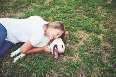 芝生の上に寝転ぶ女性と犬