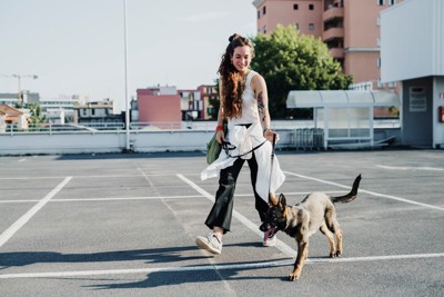 リードで犬を上手に散歩させる女性