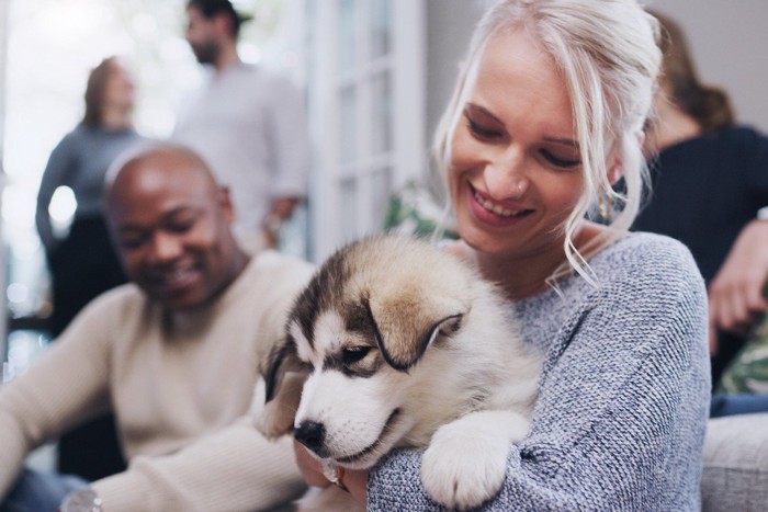 女性に抱かれる子犬と背景にいる人々