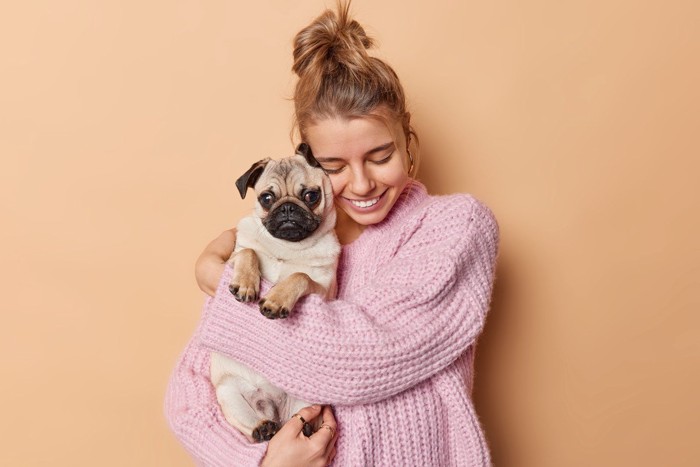 女性に抱っこされている子犬