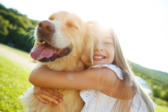 女の子に抱きしめられる犬