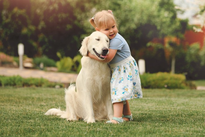 女の子に抱き着かれている大型犬