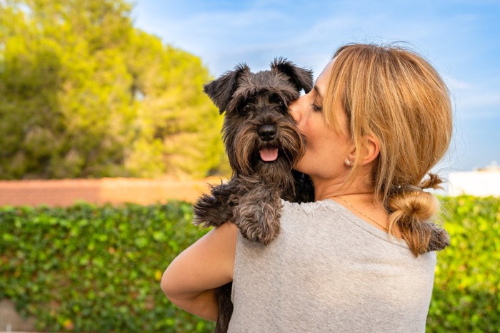 女性に抱っこされている犬