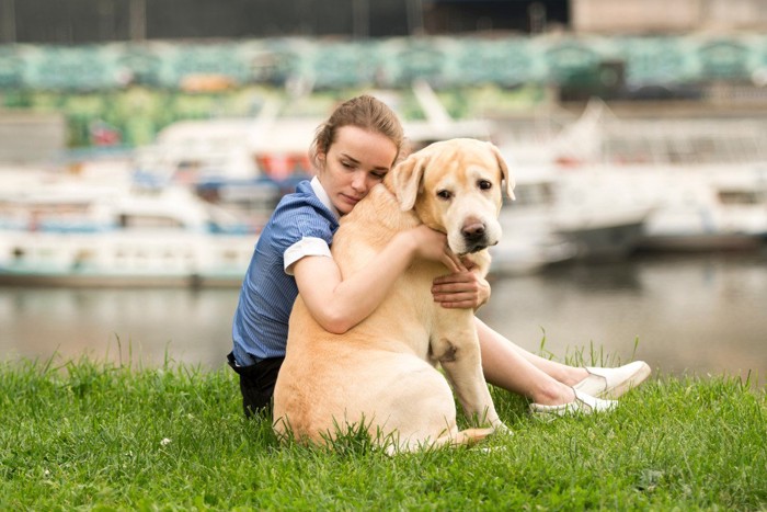 座り込んで犬をハグしている女性