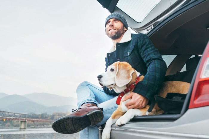 車の側で休む男性と犬