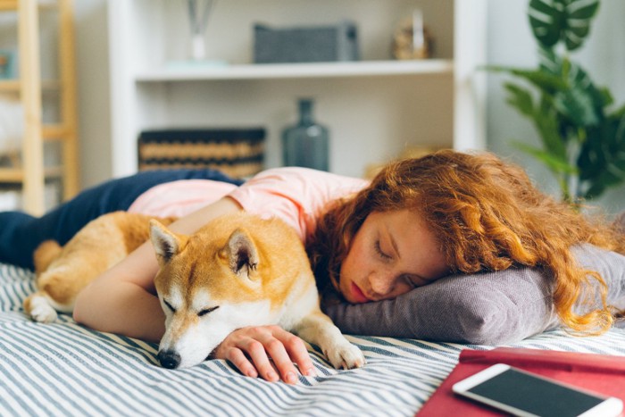 女性に寄りかかるようにして眠る犬