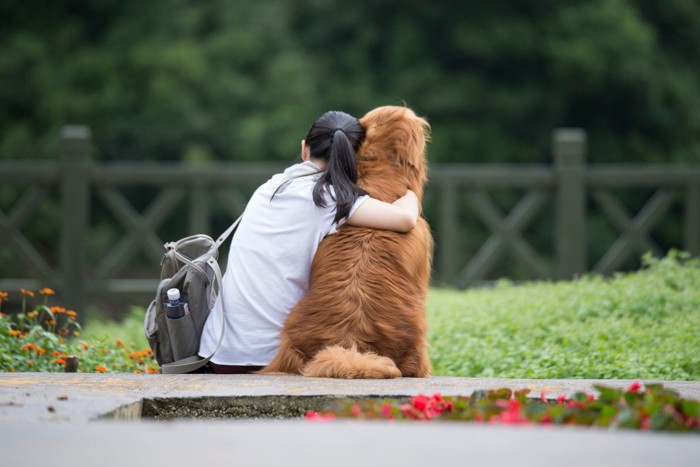 寄り添う人と犬の後ろ姿