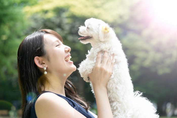 愛犬を抱き上げる笑顔の女性