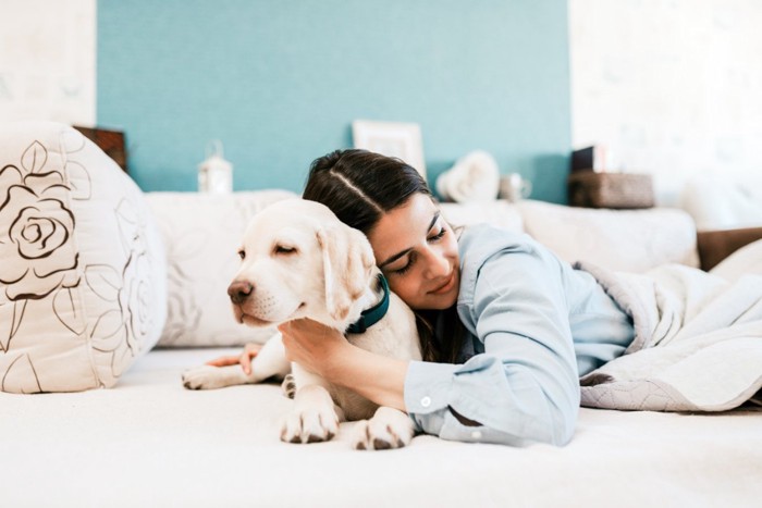 ハグする女性と嫌そうな犬