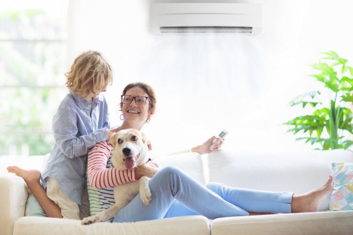 エアコンを操作する女性と家族