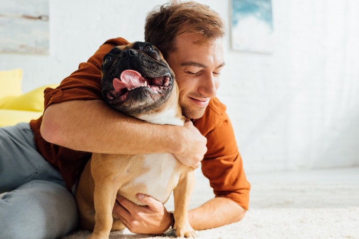 男性に抱き着かれる犬