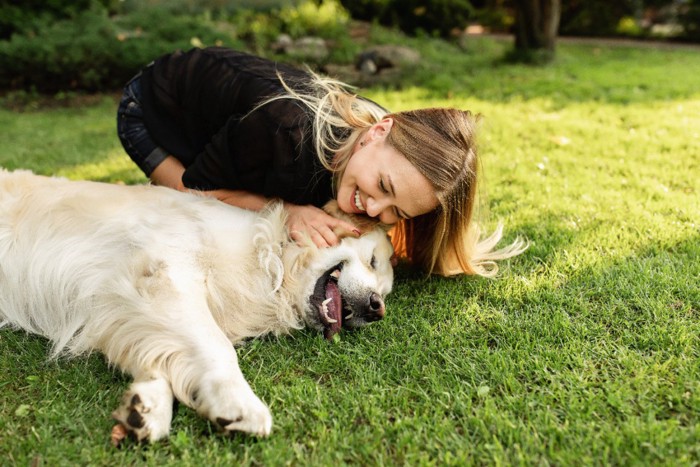 芝生の上で戯れる女性と犬